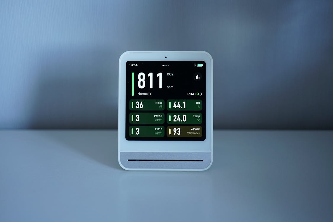 Compact digital air quality monitor displaying CO2 and PM2.5 levels in an indoor environment